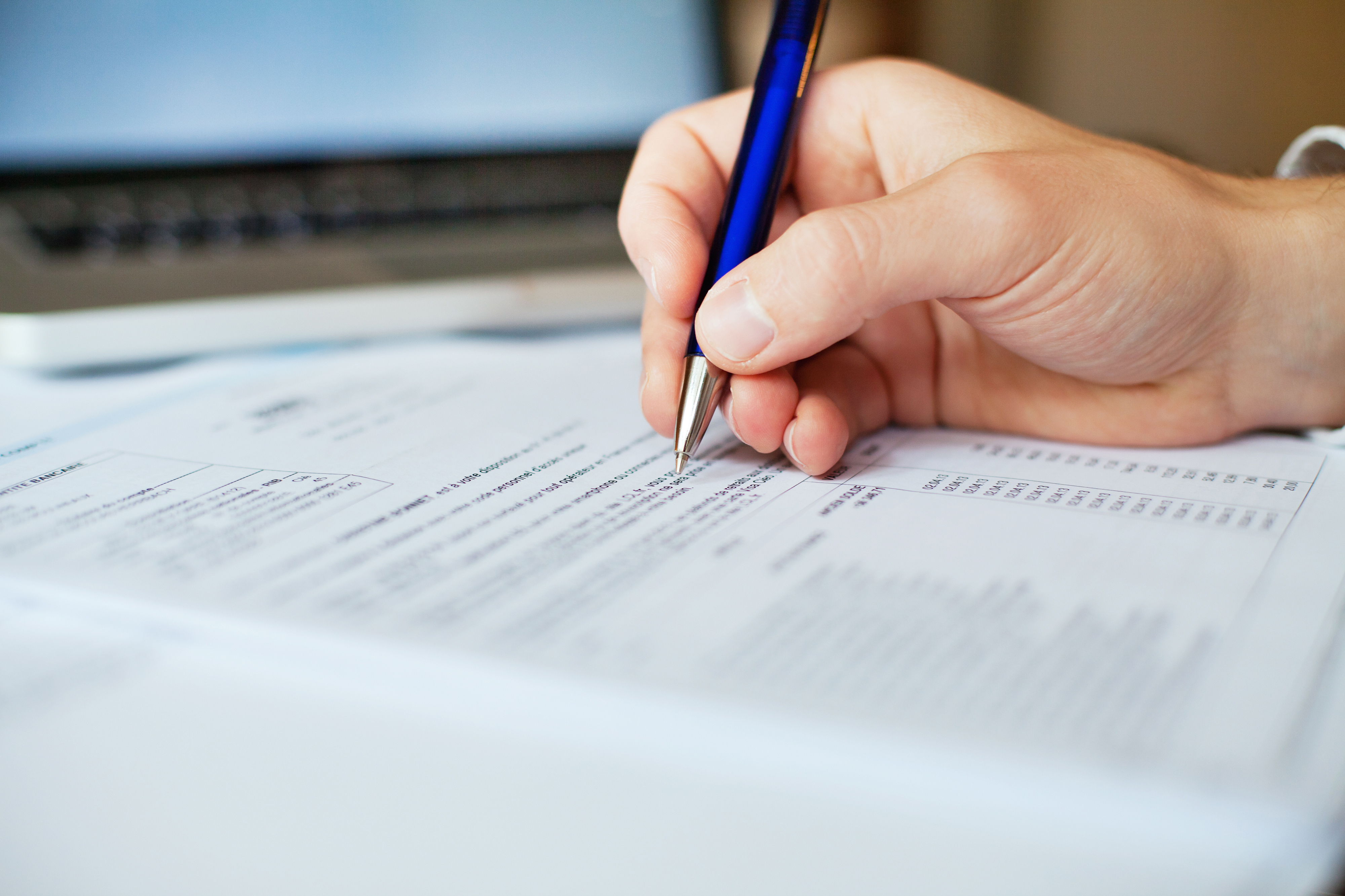 Filling out Ledger close-up of hand writing on document with blue pen