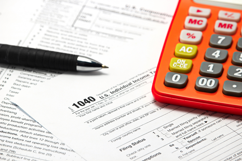 Pen and orange calculator on top of tax forms